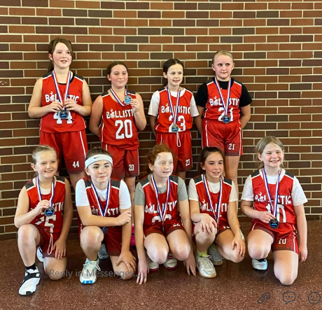A youth girls Ballistic team poses with their runner-up medals against a brick wall.